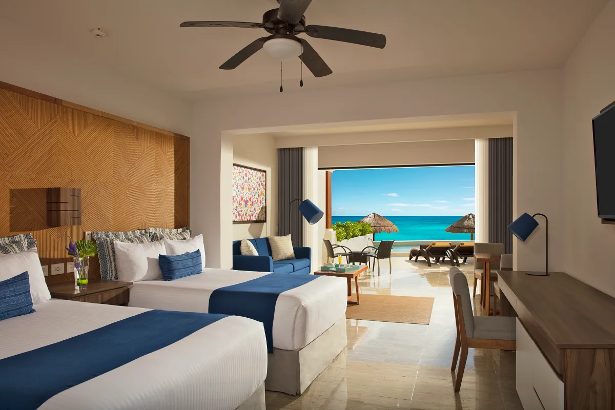 A double bed ocean front room with a swim-up pool on their patio in the background.