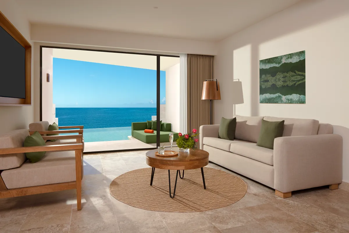 The living room of an ocean front view room with a swim up pool patio in the background.