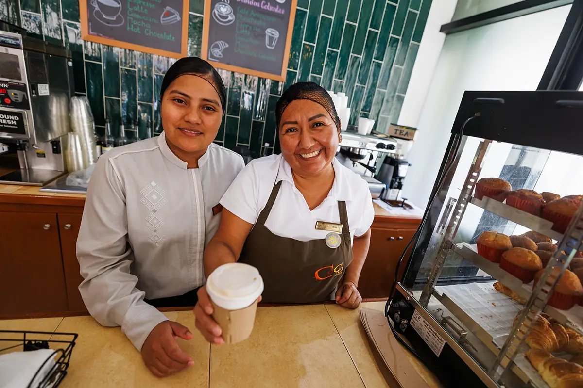 Resort staff smiling while handing a guest a cup of coffee