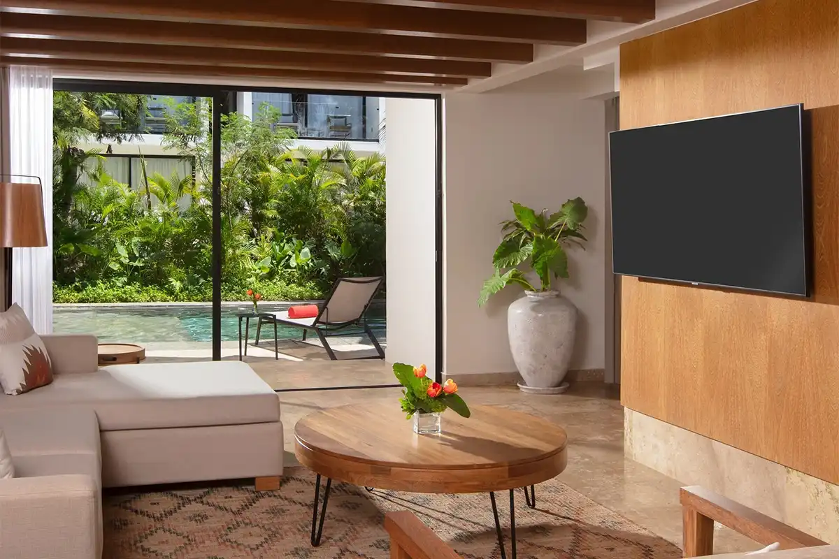 Living room of a two-story villa suite with a private pool and patio in the background.