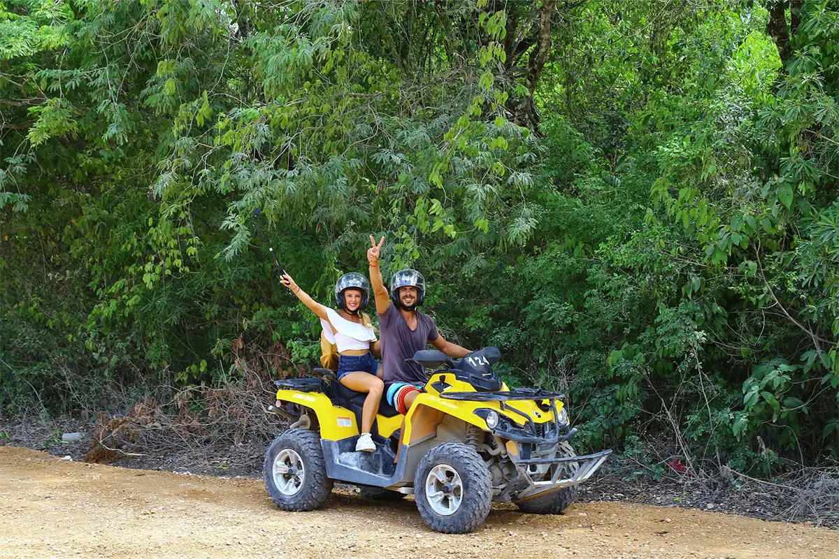 Guests with their hands up on an ATV on an off-site excursion.