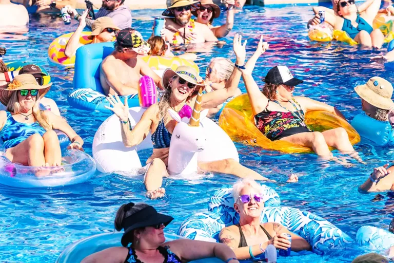 A guest on a unicorn shaped float with their hands up.
