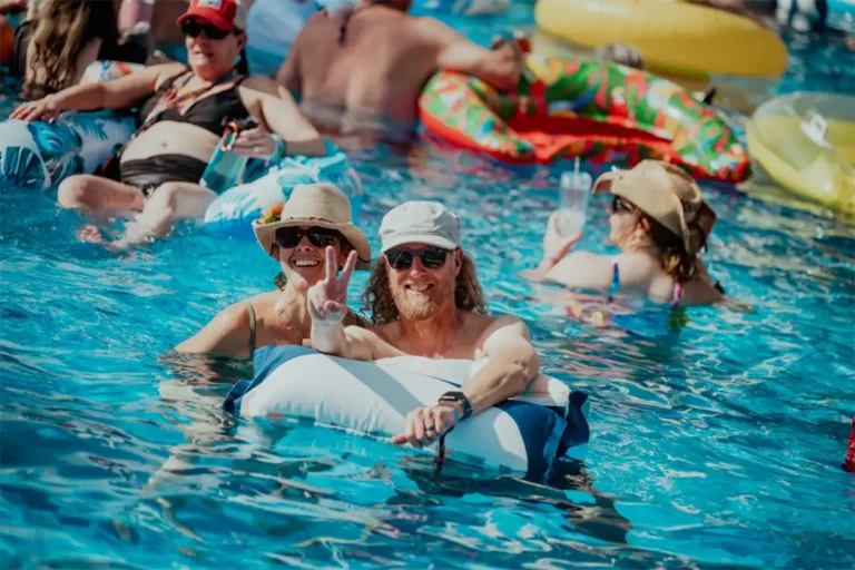 A couple using a pool float holding up peace signs with their hands.