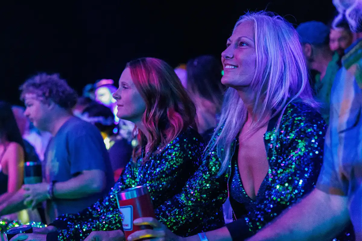 A guest in a theme night costume watching a concert on the beach.
