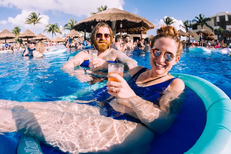 Close up of a guest on a pool float with a drink in their hand.
