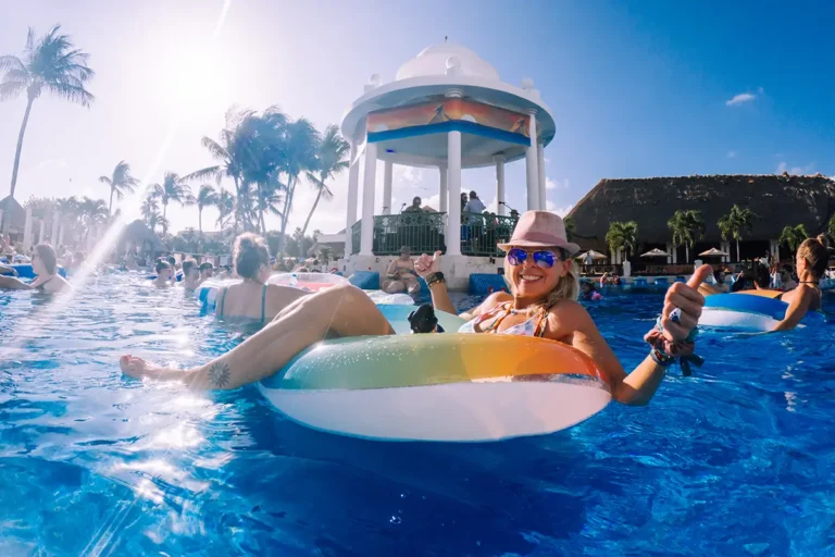 A guest in a pool float smiling at the camera with the Poolside Gazebo stage behind them.