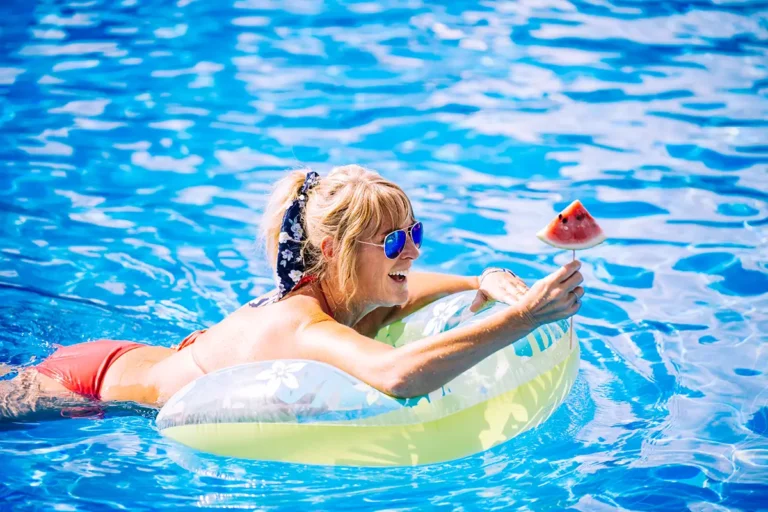 A guest floating in the pool with fruit on a stick.