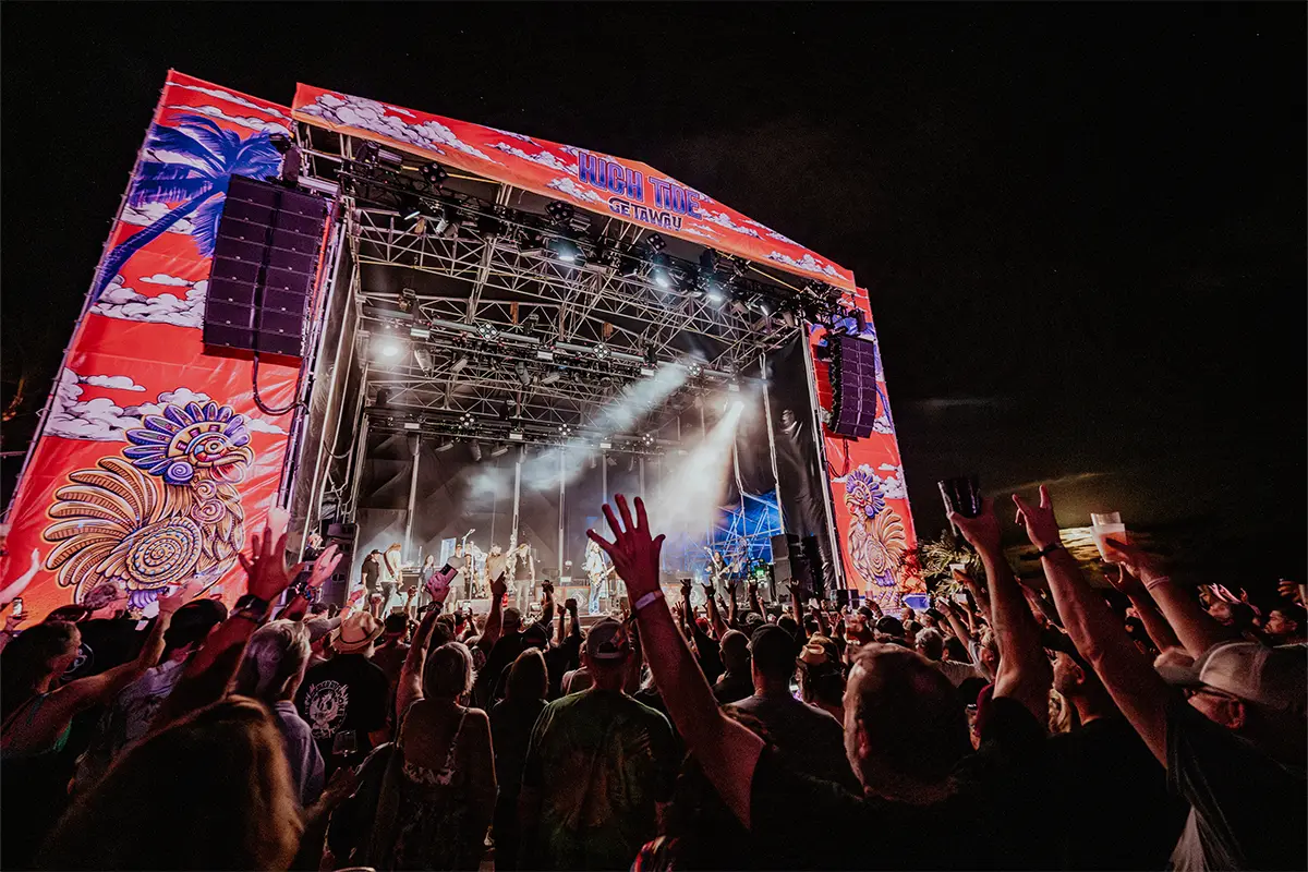 Point of view of the Main Stage from the crowd, guests with their hands up.