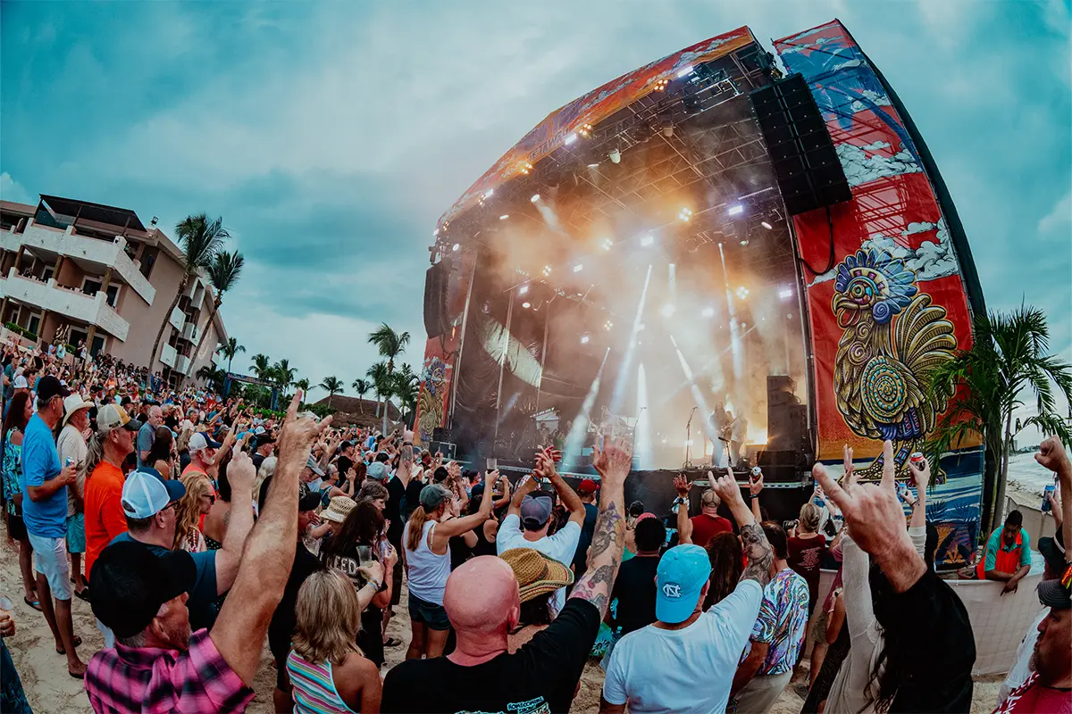 Point of view of the Main Stage from the crowd, guests with their hands up.