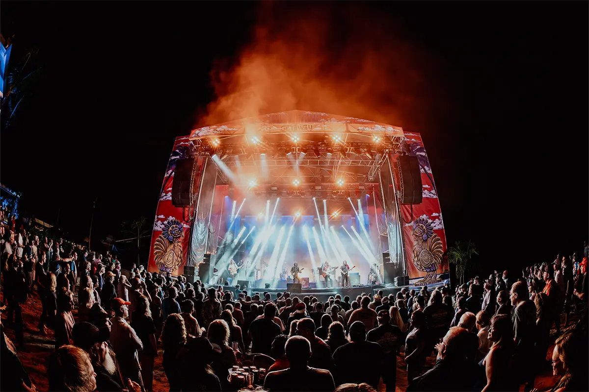 A wide angle photo of the Main Stage with bright lights shining down on the band.