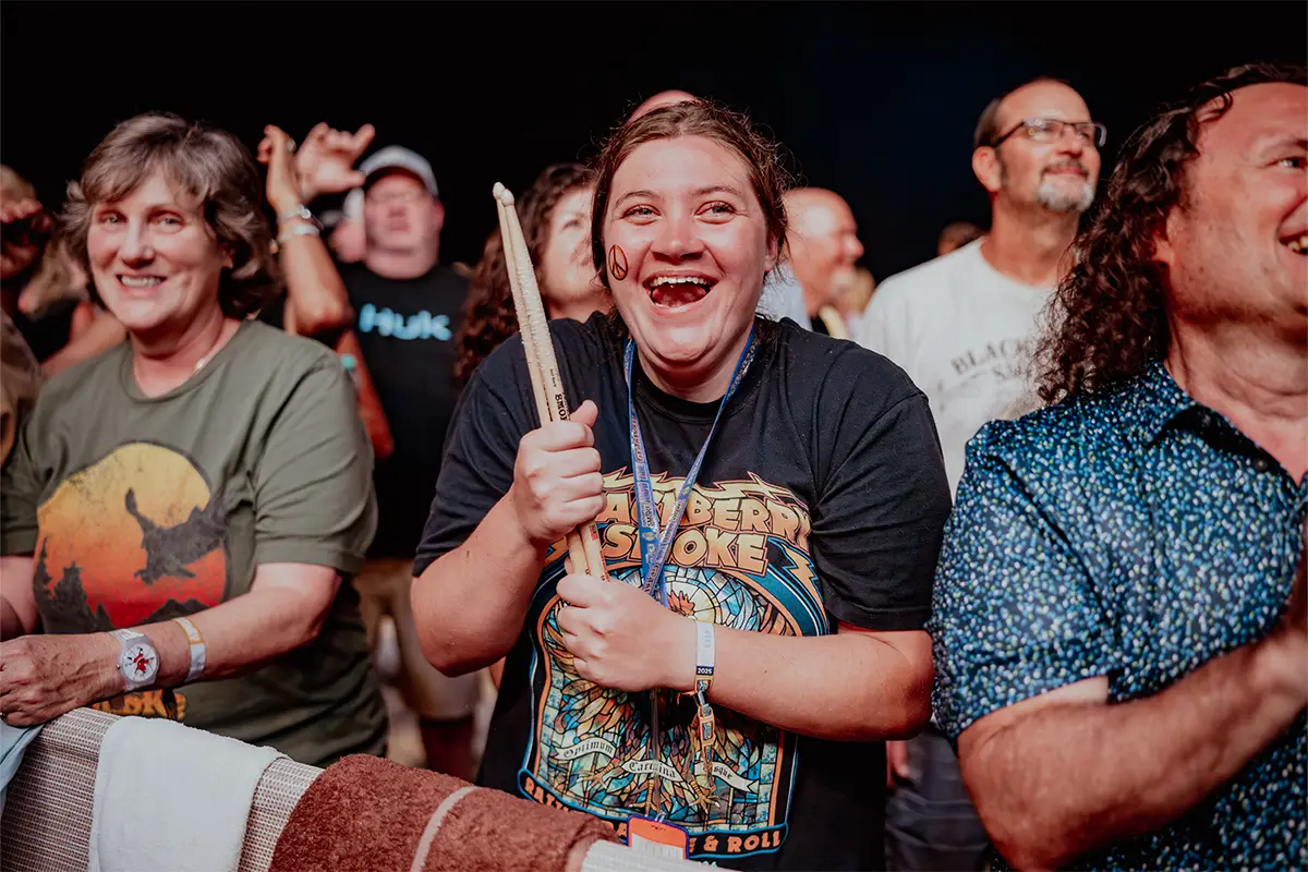 A close up photo of a fan in the crowd holding drumsticks given to her by Blackberry Smoke.