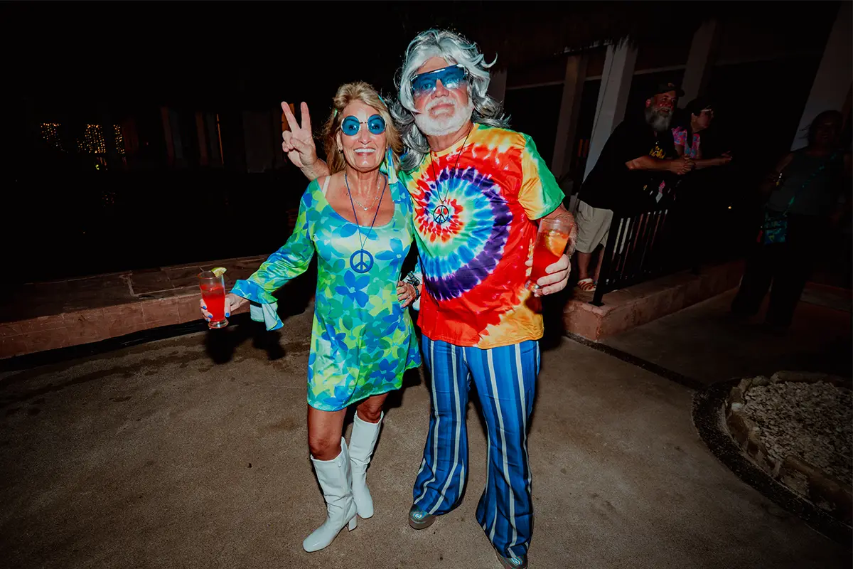A couple wearing 70s inspired theme night outfits.