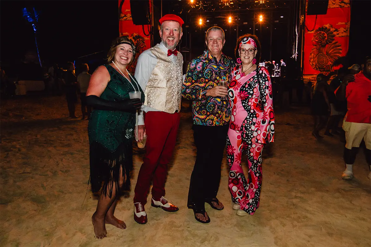 Guests posing in theme night costumes on the beach.
