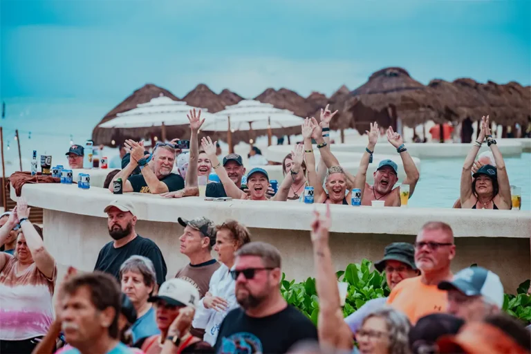 A group of guests in a swim-up pool suite with their hands up.